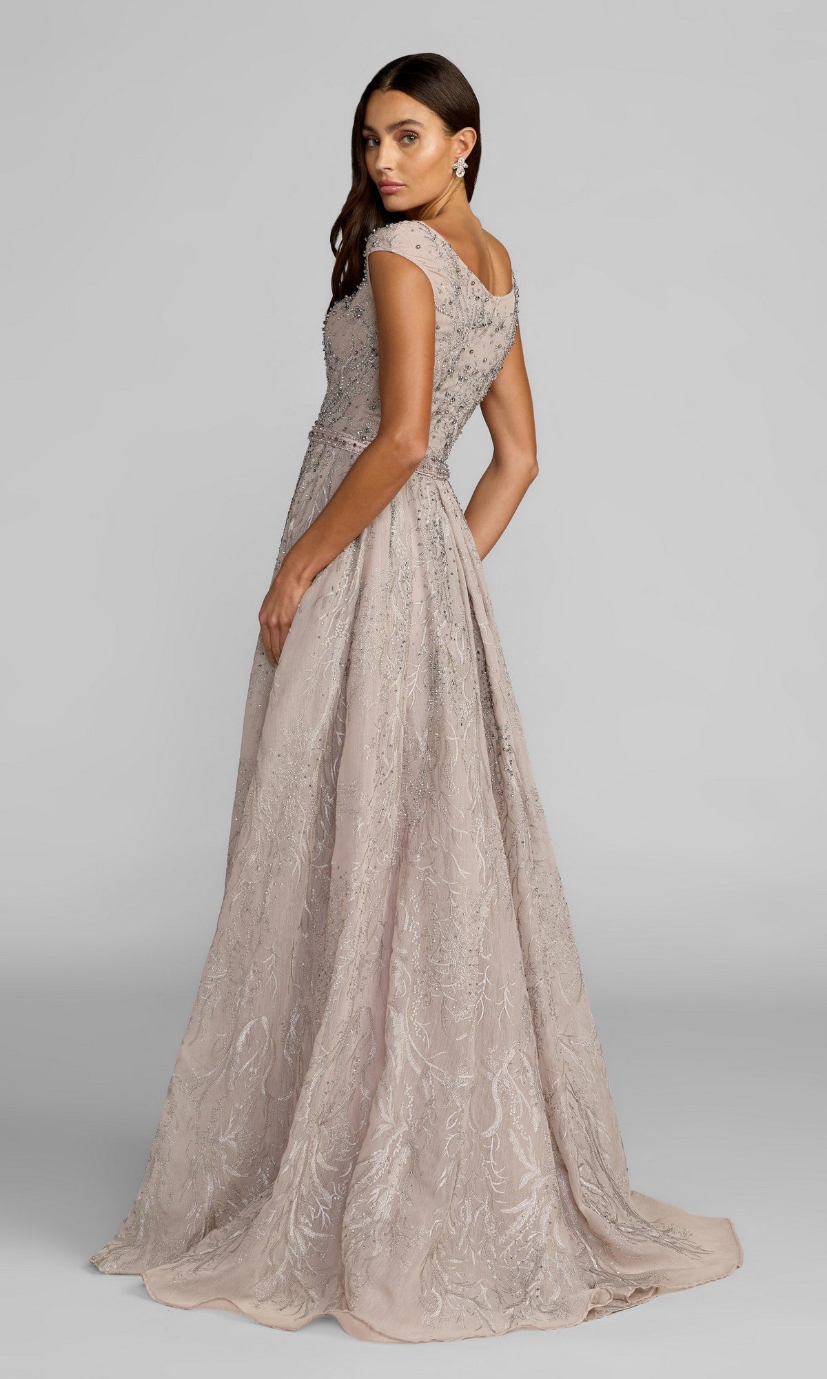 A woman stands slightly turned to the side against a plain gray background, wearing the Mac Duggal 20374 long formal dress in light mauve, featuring floor-length styling with intricate embroidery and beaded embellishments.